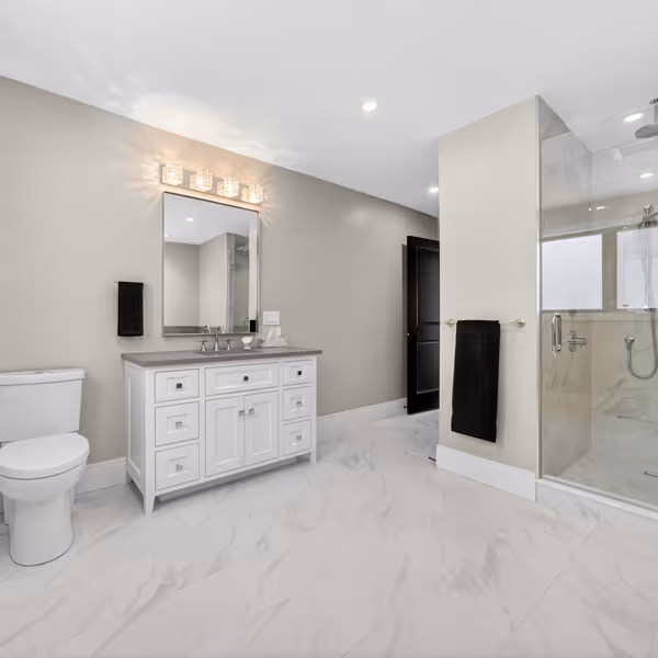 Modern laundry room with white cabinets, black sink faucet, washing machine, a green potted plant, and a framed botanical print.