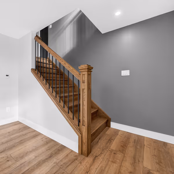 A bright modern bathroom with double vanity sinks, two rectangular mirrors, wall sconces, white cabinetry, and patterned tile floor.