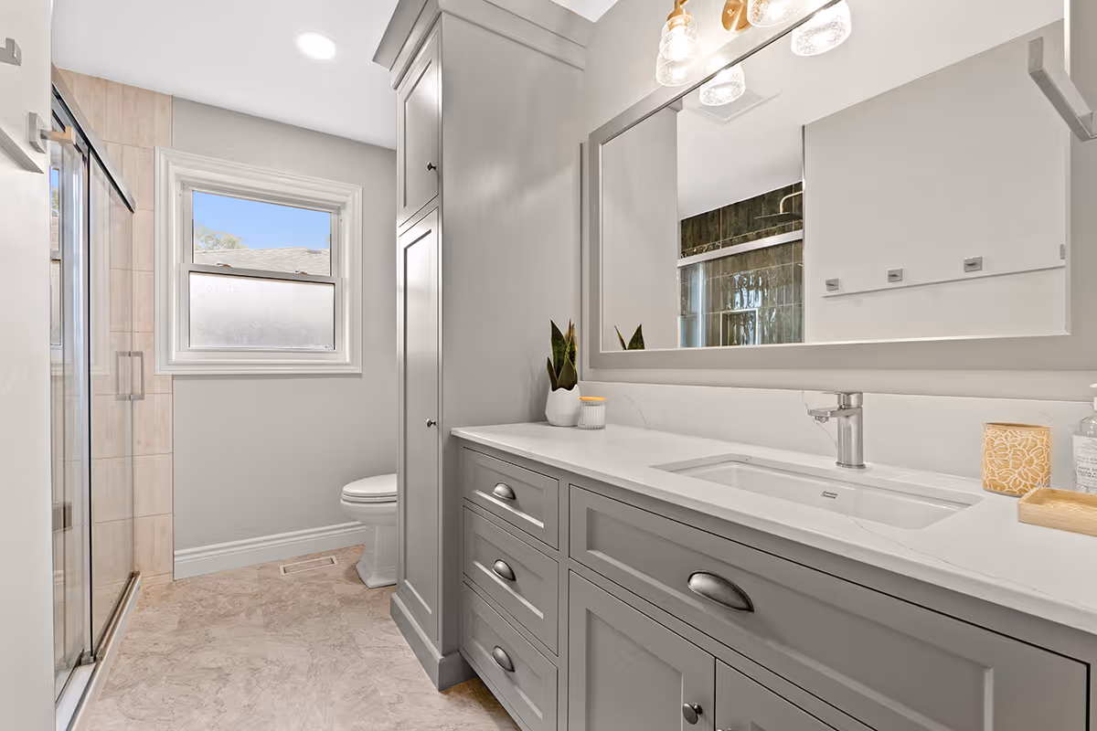 Modern basement living area with beige sofas, black round coffee table, wall-mounted TV, and exercise equipment in the background.