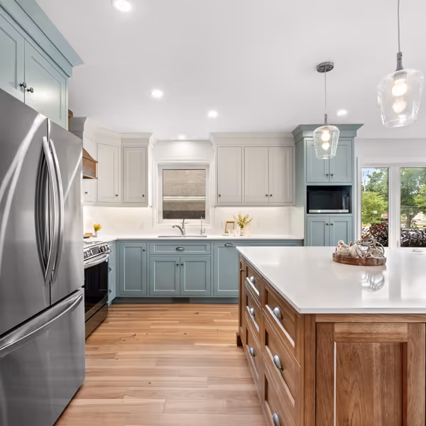 Modern kitchen sink with dual stainless steel basins and a tall curved chrome faucet under white shuttered window.