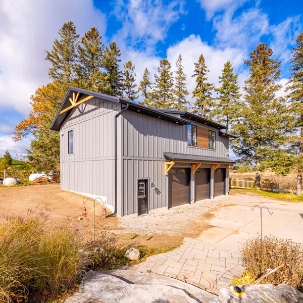 Modern kitchen sink with dual stainless steel basins and a tall curved chrome faucet under white shuttered window.