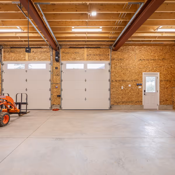Cozy living room with a white fireplace decorated with greenery and red roses, a mounted flat-screen TV above it, a leather sofa, framed artwork on the walls, glass coffee table, and soft lighting.
