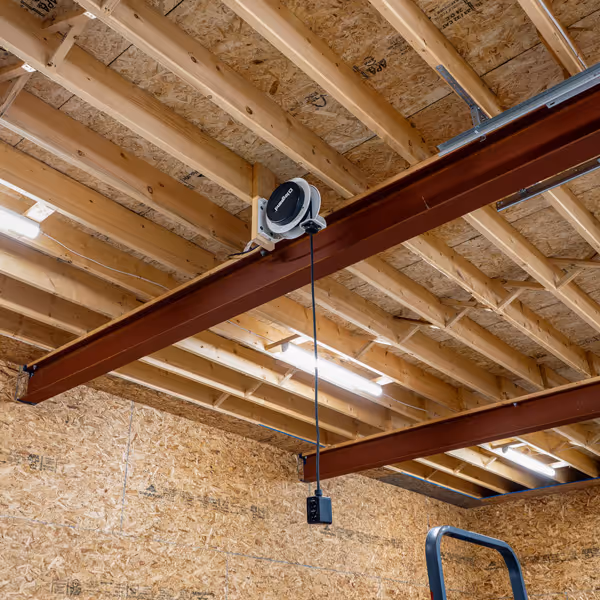 Cozy living room with cream sofa, patterned armchairs, wooden floor, and a decorated Christmas tree near a large window.