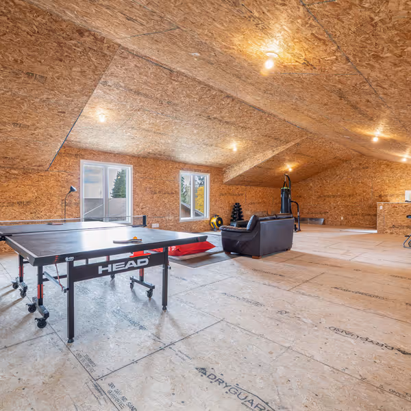 Modern living room corner with a gray sofa adorned with patterned pillows, a wooden shelf with decorative items, and a lit fireplace with a textured gray wall.