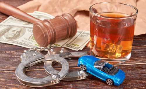A judge's gavel, handcuffs, cash, a glass of whiskey, and a toy car symbolize the legal and financial consequences of a DUI arrest in California.