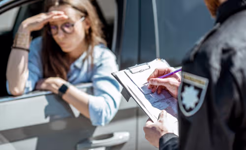 A law enforcement officer writes a citation while speaking with a concerned driver during a traffic stop, illustrating a DUI investigation.