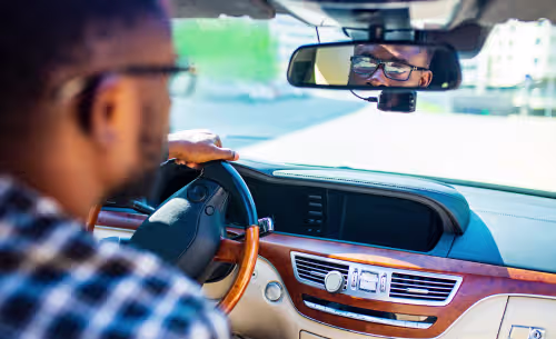 A driver looks ahead while holding the steering wheel, illustrating a person operating a motor vehicle in a DUI-related context.
