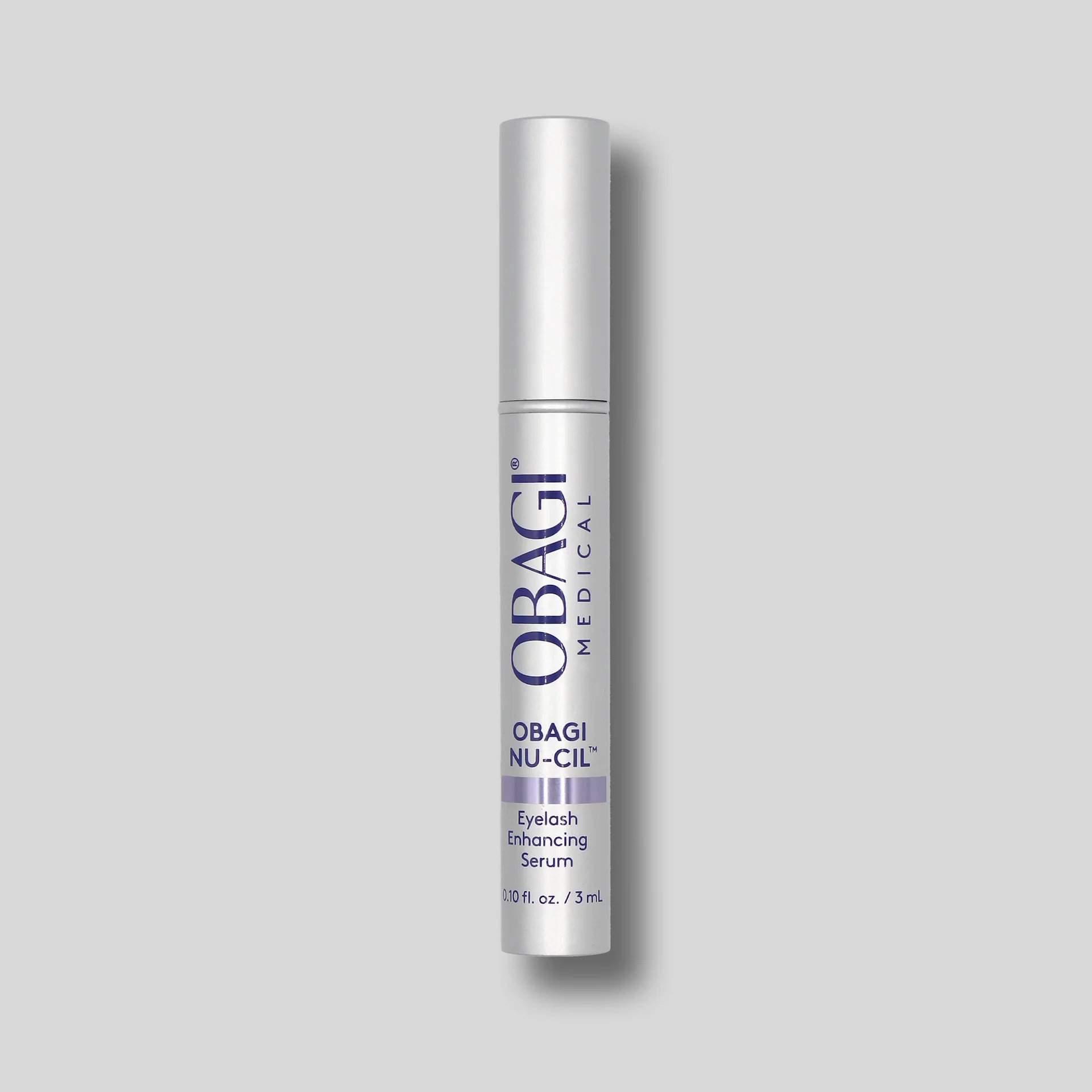 Obagi NU-CIL eyelash enhancing serum in a sleek silver tube on a gray background.