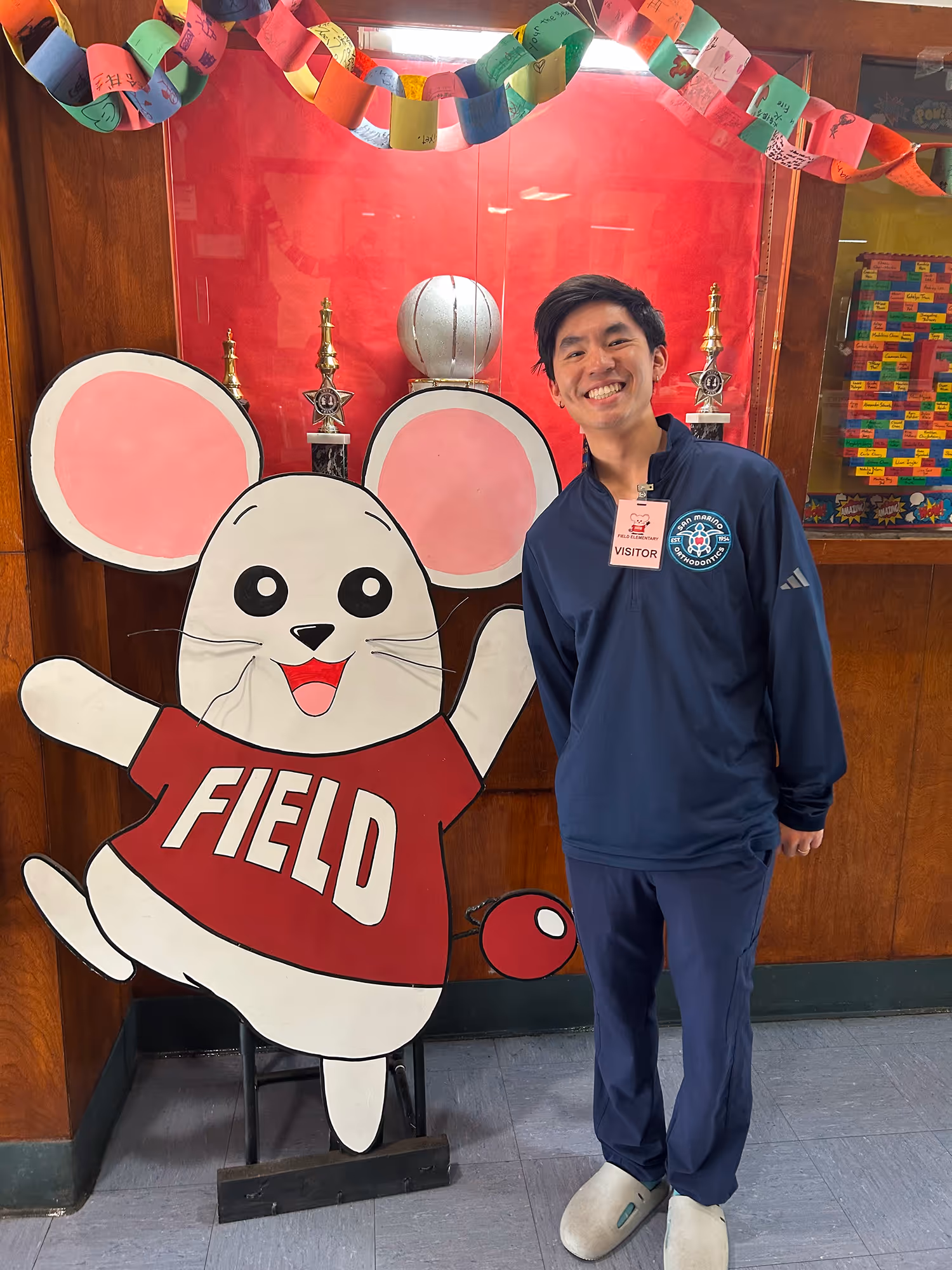 A man standing in front of a sign with a mouse on it.