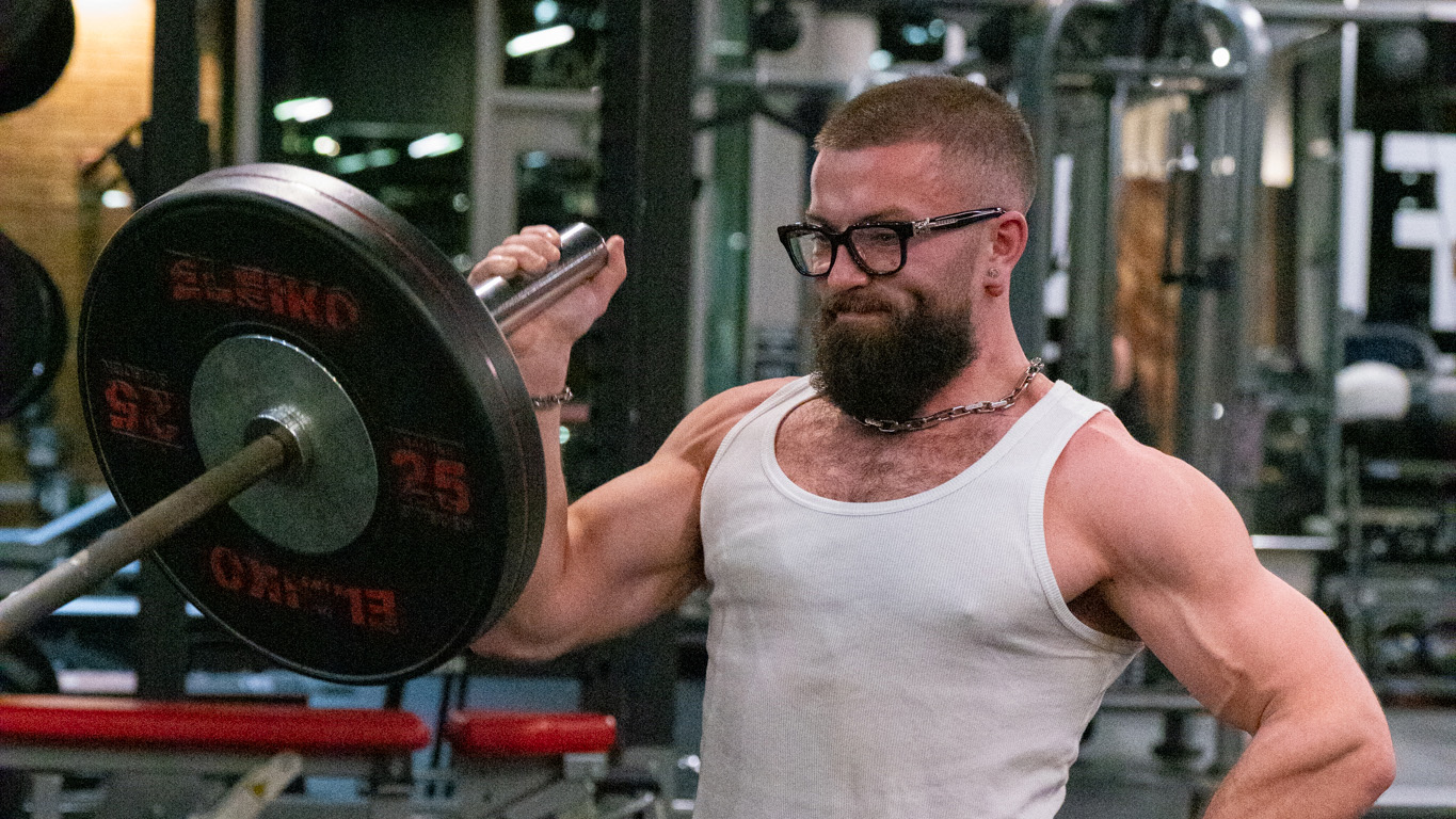 Jeremy performing landmine barbell press inside gym