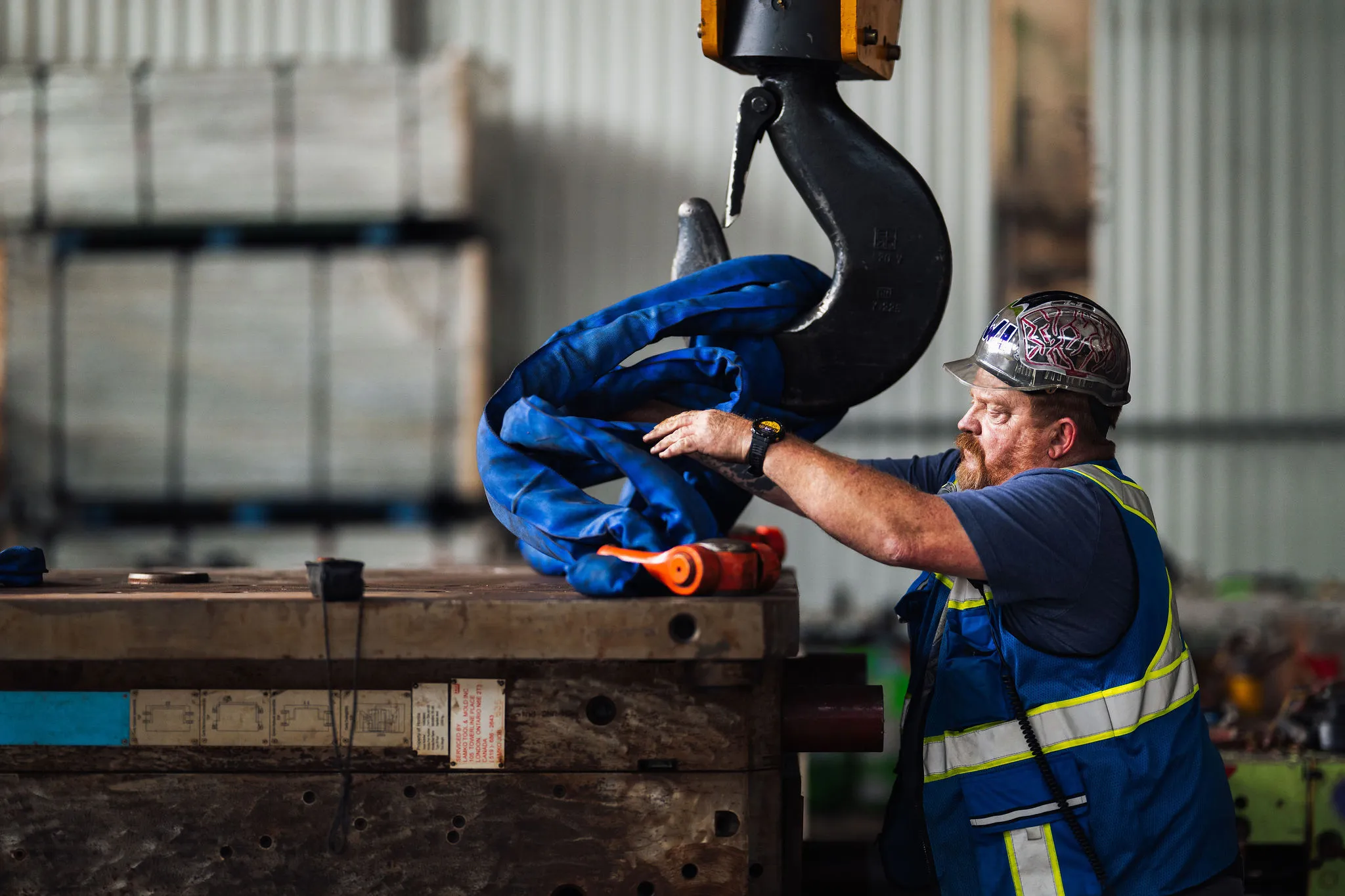 Warehouse worker operating overhead crane for industrial products handling