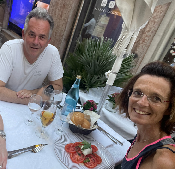 Couple enjoying a meal with tomato salad, bread, and drinks at a restaurant