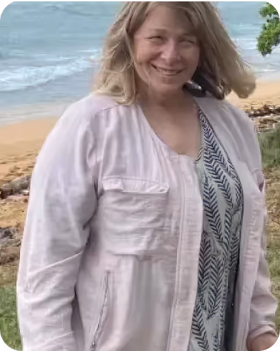 A woman standing on a beach next to the ocean.