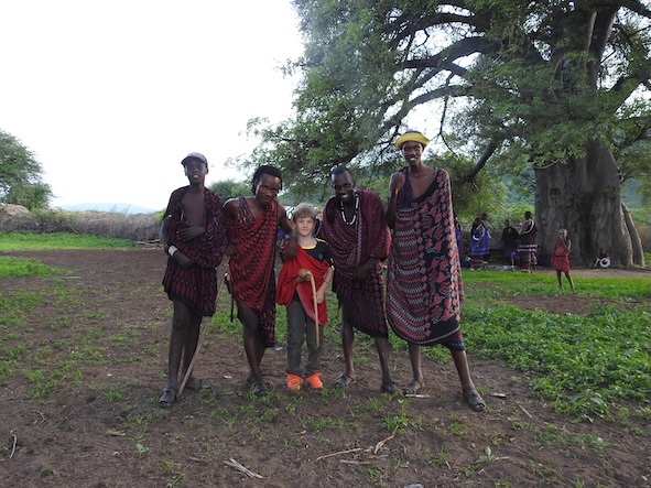 Ein Kind umgeben von Massai auf einer Familienreise