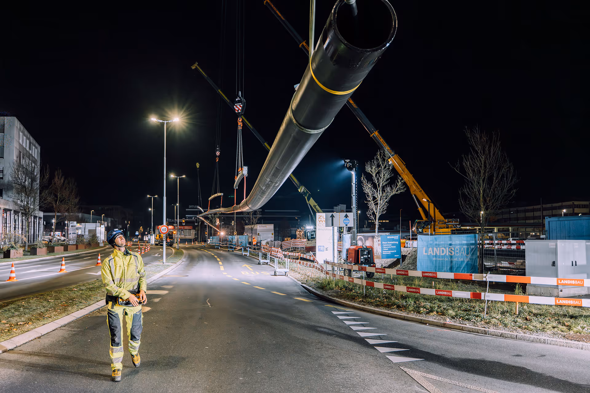 Ein Rohrabschnitt von 130 m wird per Kran über die gesperrte Kreuzung gehoben und für den Einzug in den Untergrund positioniert. Anschliessend wird die Fernwärmeleitung in das Kunststoffrohr eingezogen.