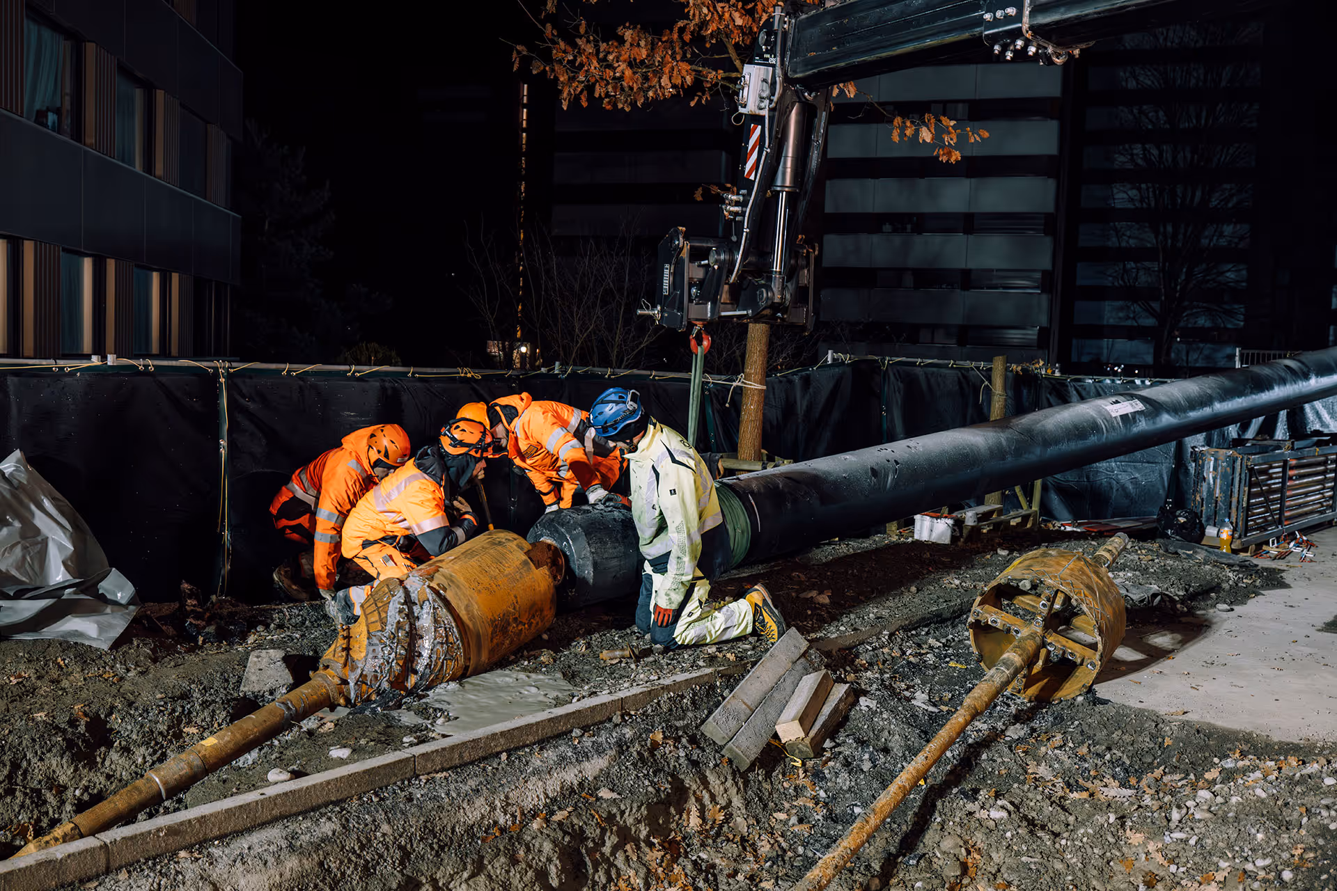 Mehrere Fachleute koppeln den Bohrkopf an das Hüllrohr, bevor der Einzug durch den Untergrund beginnt.