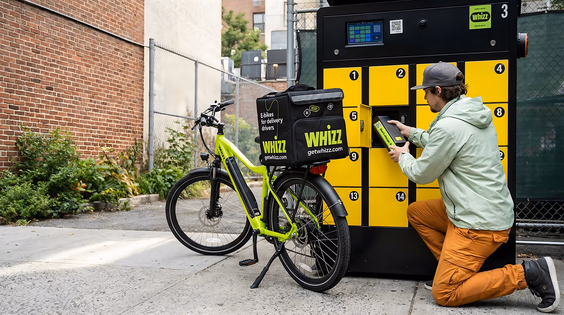 Person kneeling and removing a battery from a yellow locker charging station next to a lime green delivery e-bike with Whizz branding.