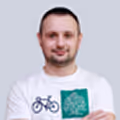 Smiling man wearing a white shirt with bicycle and green graphic design icons.