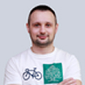 Smiling man wearing a white shirt with bicycle and green graphic design icons.