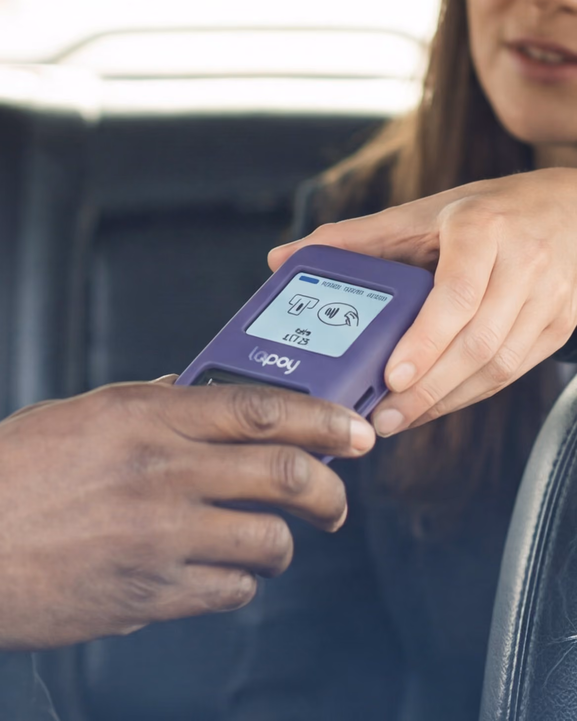 Two hands holding a purple lopay contactless payment device branded inside a taxi.
