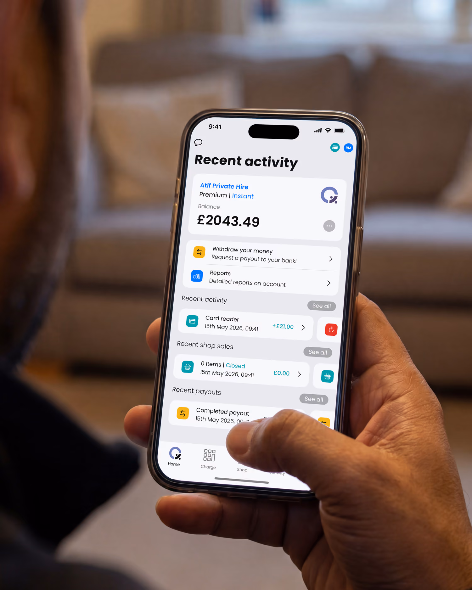 Hand holding smartphone showing taxi payment processing app with recent activity and £2043.49 balance.