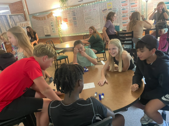 Students assembling crafts around a table.