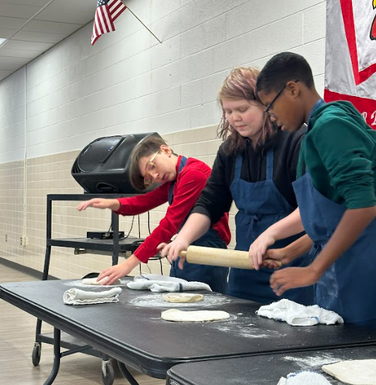 Students flipping pizza dough.
