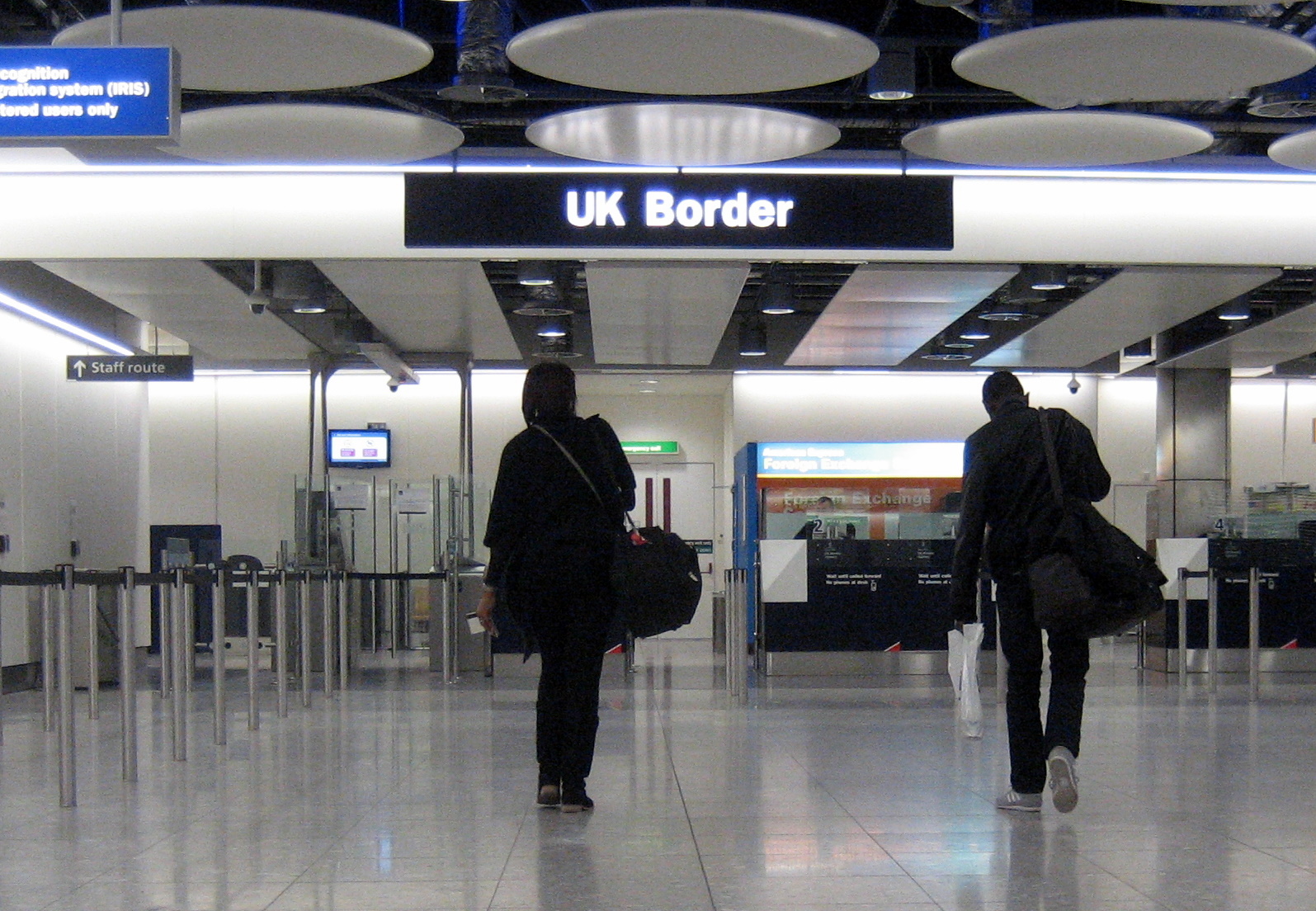 UK Airport Border with two people walking toward it