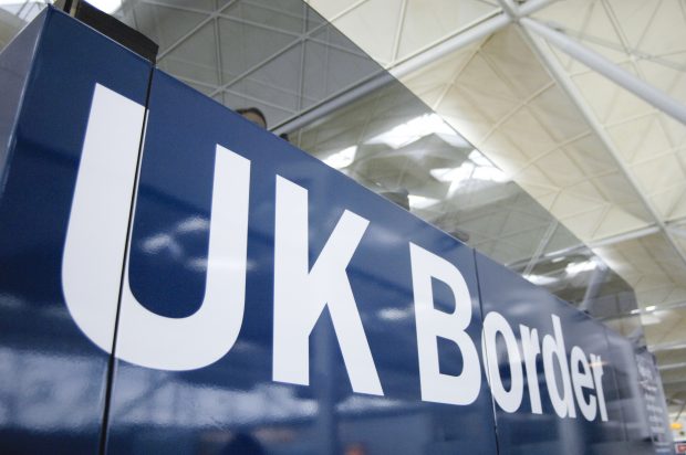 A blue UK Border sign at an airport arrivals hall
