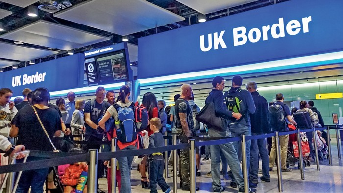 Passengers queuing at UK Border passport control in an airport