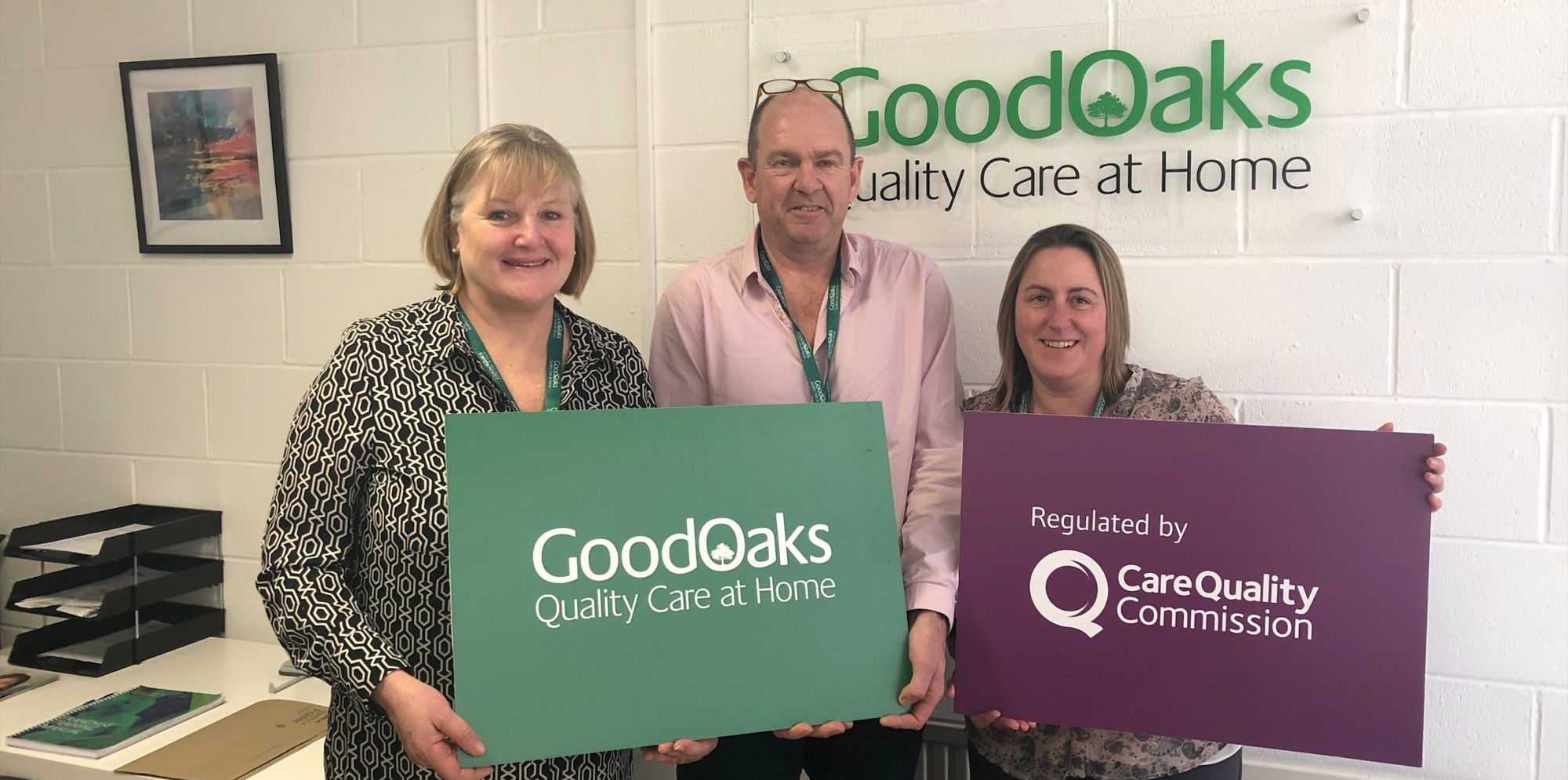 The GoodOaks Homecare team with their branded signs and a Care Quality Commission award