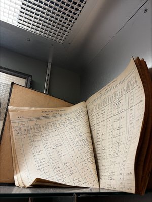 Aged historical teacher record book open on a shelf