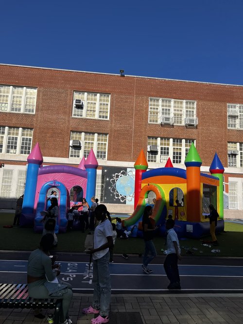 Students enjoying bounce houses at school carnival outdoor event