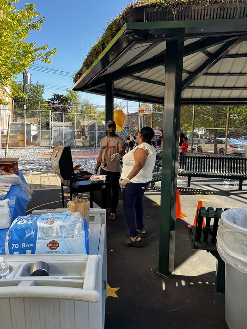 Two adults grilling food at an outdoor school carnival event