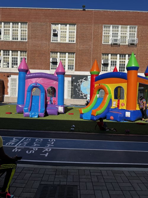 Two colorful inflatable bounce houses at school carnival event