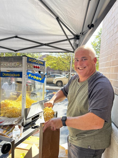 Smiling volunteer serving popcorn at school carnival booth