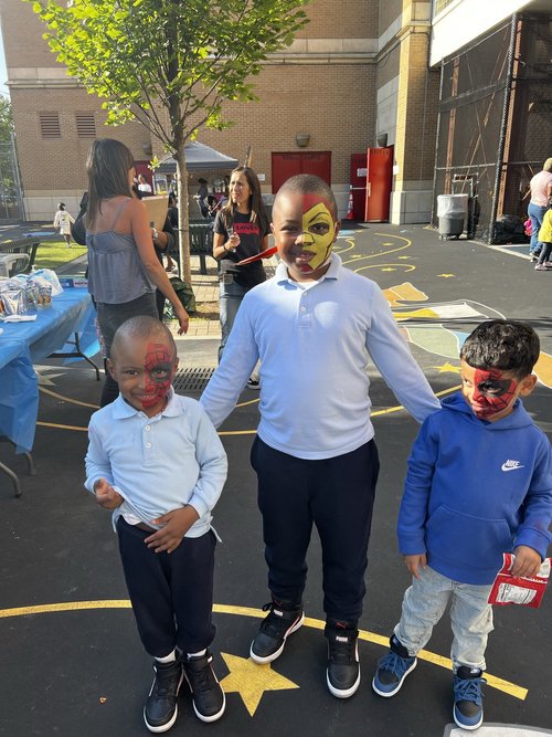 Three students with face paint smiling at school carnival