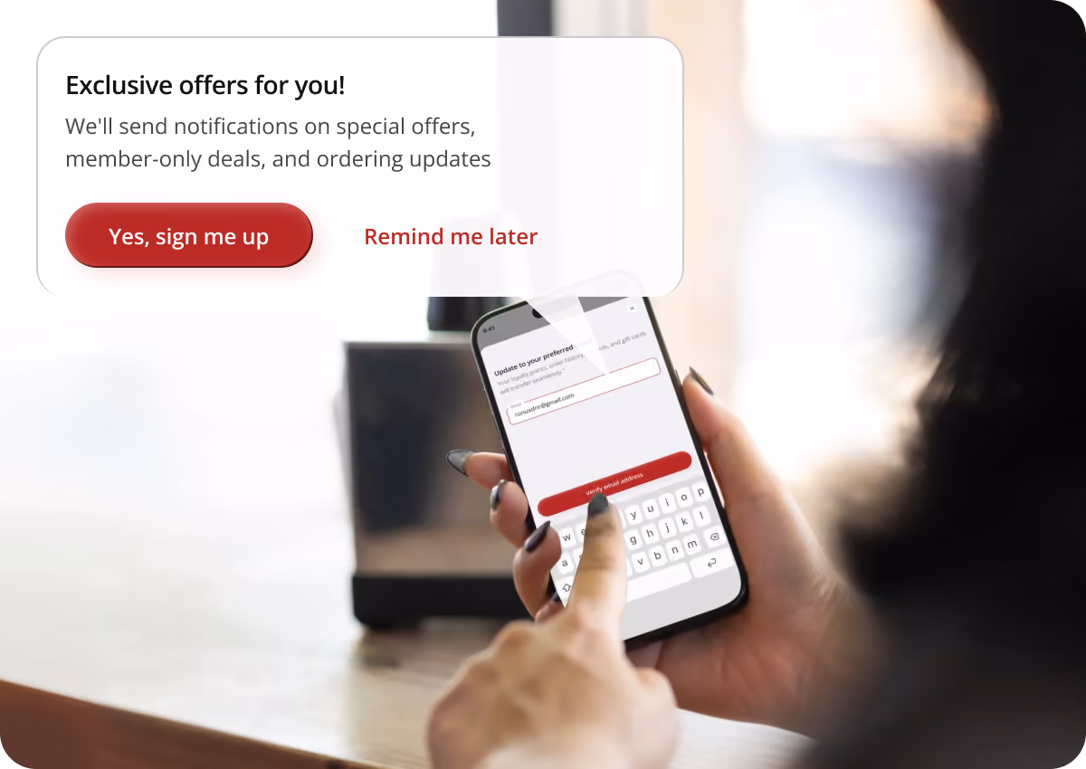Person holding a smartphone and tapping to enter an email address on a subscription popup offering exclusive offers, notifications on special offers, member-only deals, and ordering updates with buttons labeled Yes, sign me up and Remind me later.