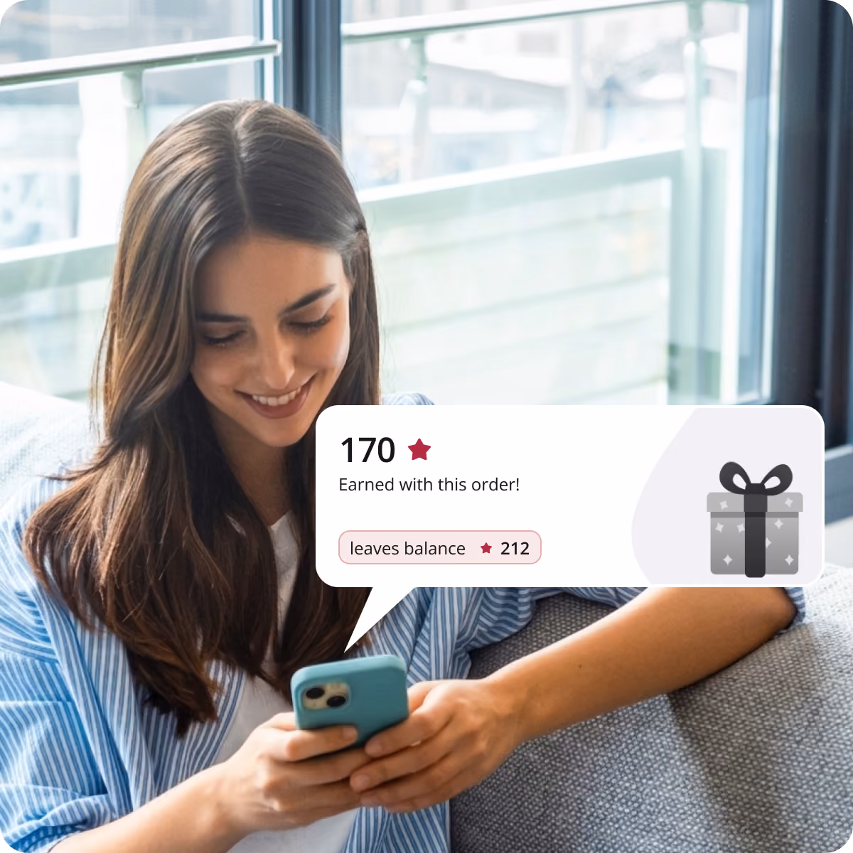 Smiling young woman sitting on a couch looking at her phone, with a digital notification showing '170 stars earned with this order' and 'leaves balance 212' next to a gift icon.