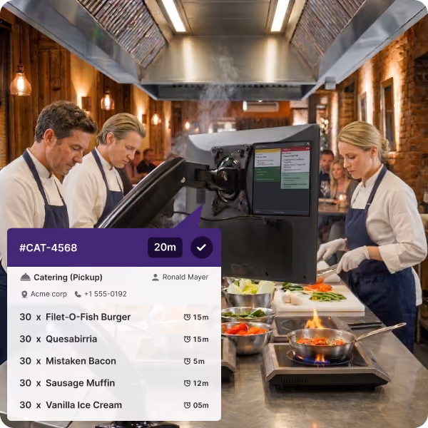 Three chefs in aprons working in a brick-walled kitchen with a cooking station and a monitor displaying catering order details including item names, quantities, and preparation times.