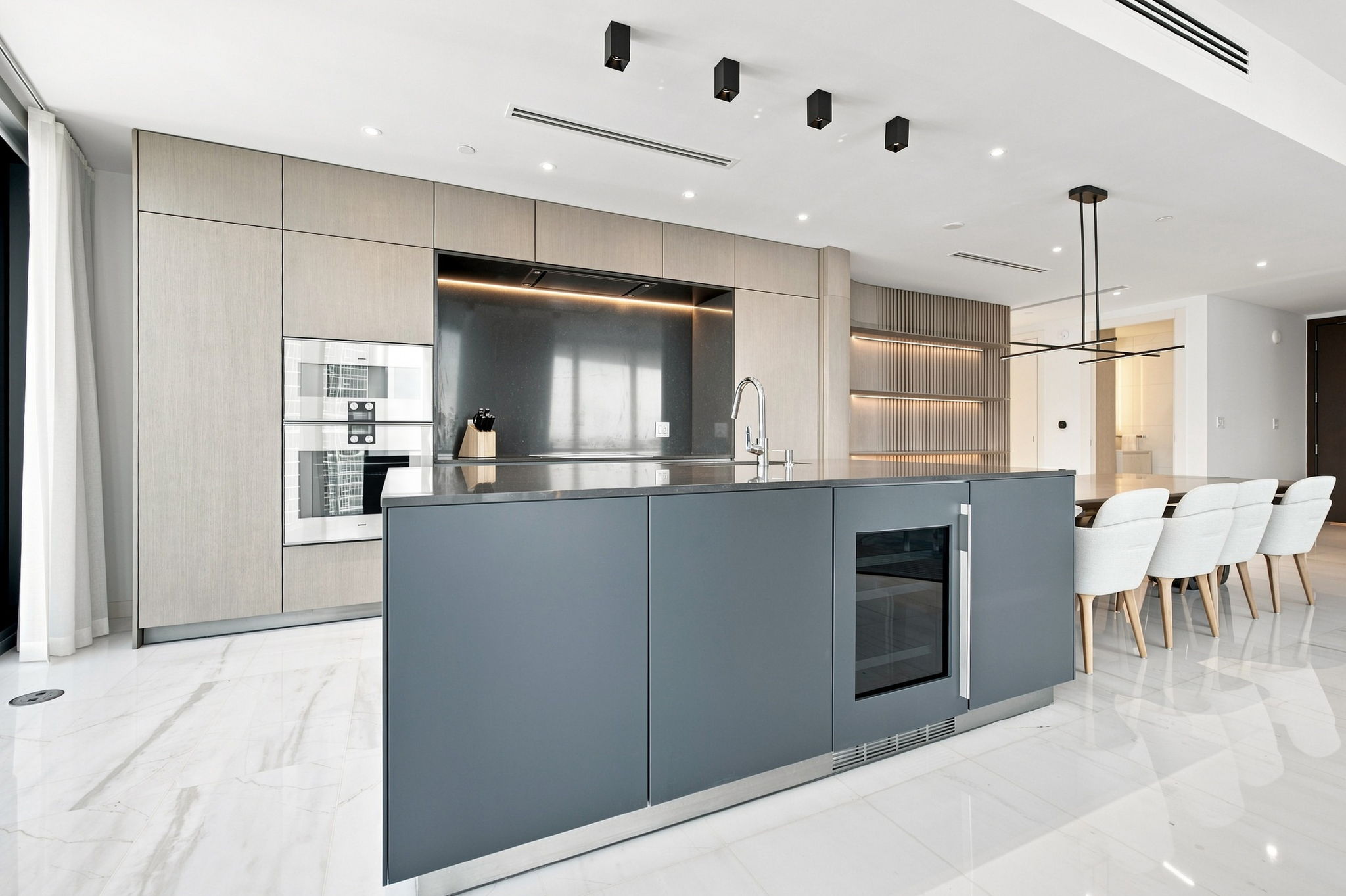 Kitchen island with wine fridge and dining table — Residence 3807