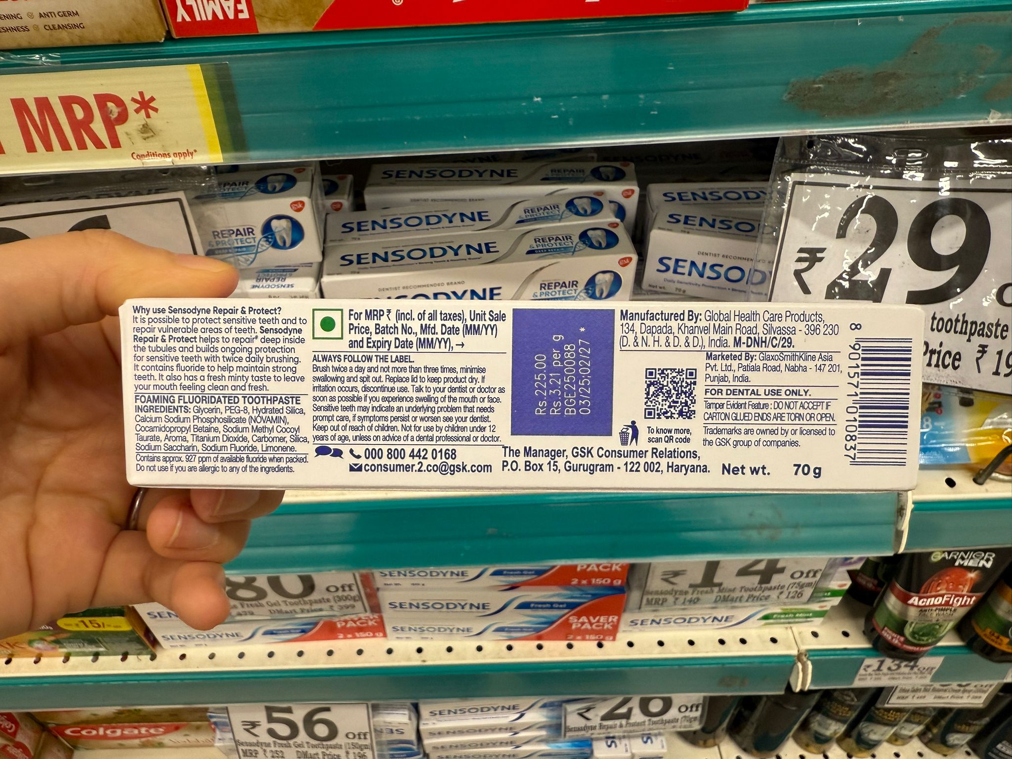 Sensodyne Repair & Protectの歯磨き粉パッケージの側面。英語で製品の効能説明、使用方法、成分（例：フッ化ナトリウム、PEG-8、シリカなど）、製造者と販売者情報、価格（₹225.00）、製造年月と有効期限、バーコード、問い合わせ先、使用上の注意などが細かく記載されている。記載言語は英語のみ。