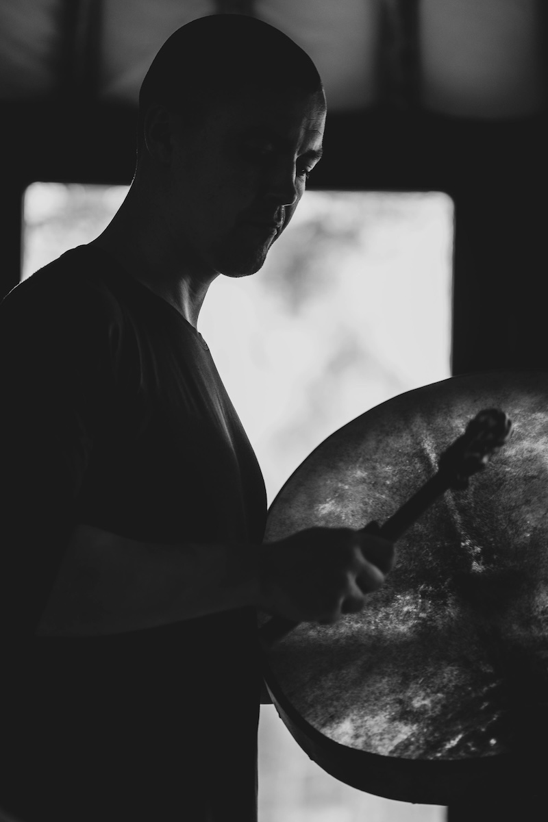 A man plays a frame drum in silhouette inside the yurt at The Return of Men retreat, Portugal, November 2024.
