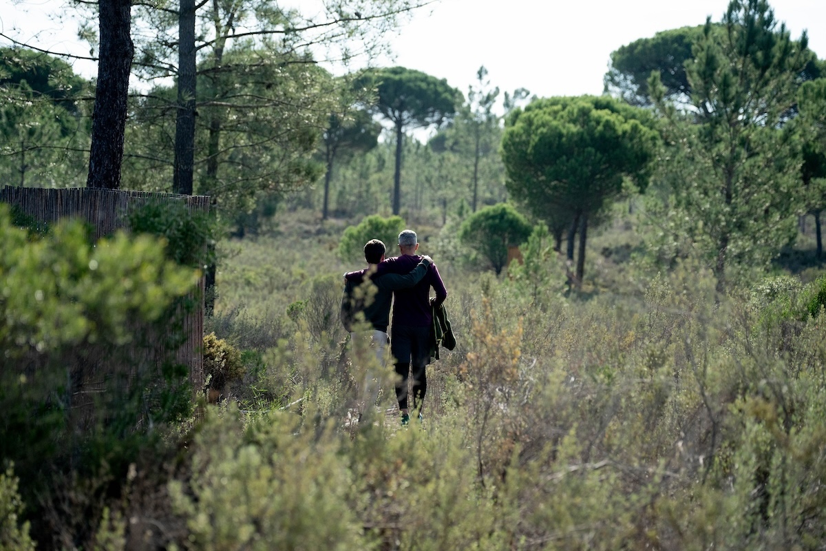 Two men walk into the scrubland between the pines at The Return of Men retreat, Wim's Land, Comporta, 2024.