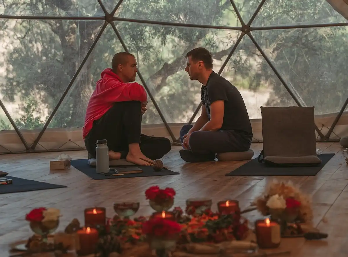 Martin Thomsen sitting with an entrepreneur in front of a floral altar, engaged in a deep and meaningful conversation about growth and transformation.