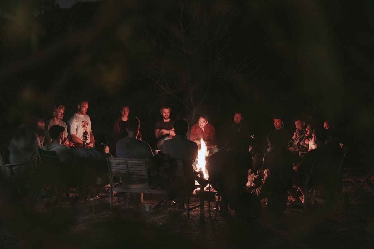The circle of men gathered around the campfire at night at The Return of Men retreat, Arrábida, October 2025.