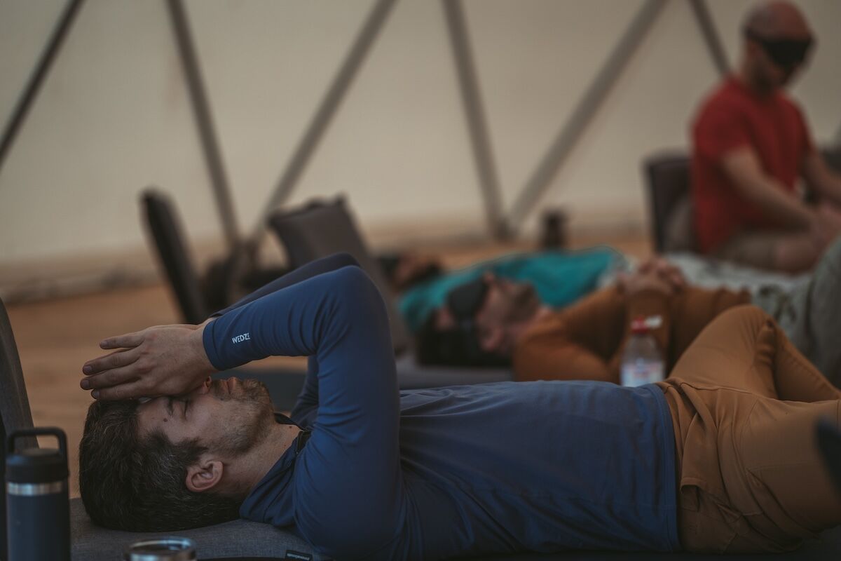 Men lie back on mats in the dome, hands over eyes, at The Return of Men retreat, Arrábida, October 2025.