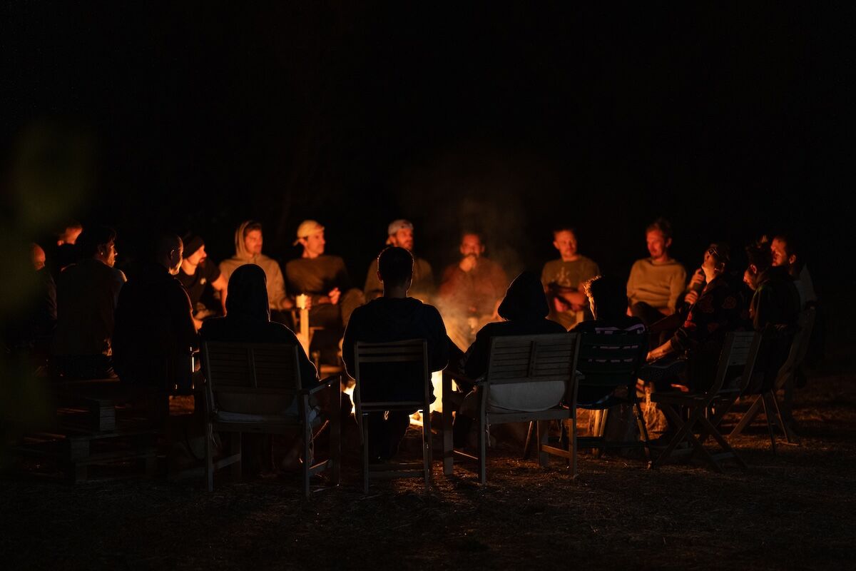 The men sit in a wide circle around the night fire at The Return of Men retreat, BioVilla, Portugal.