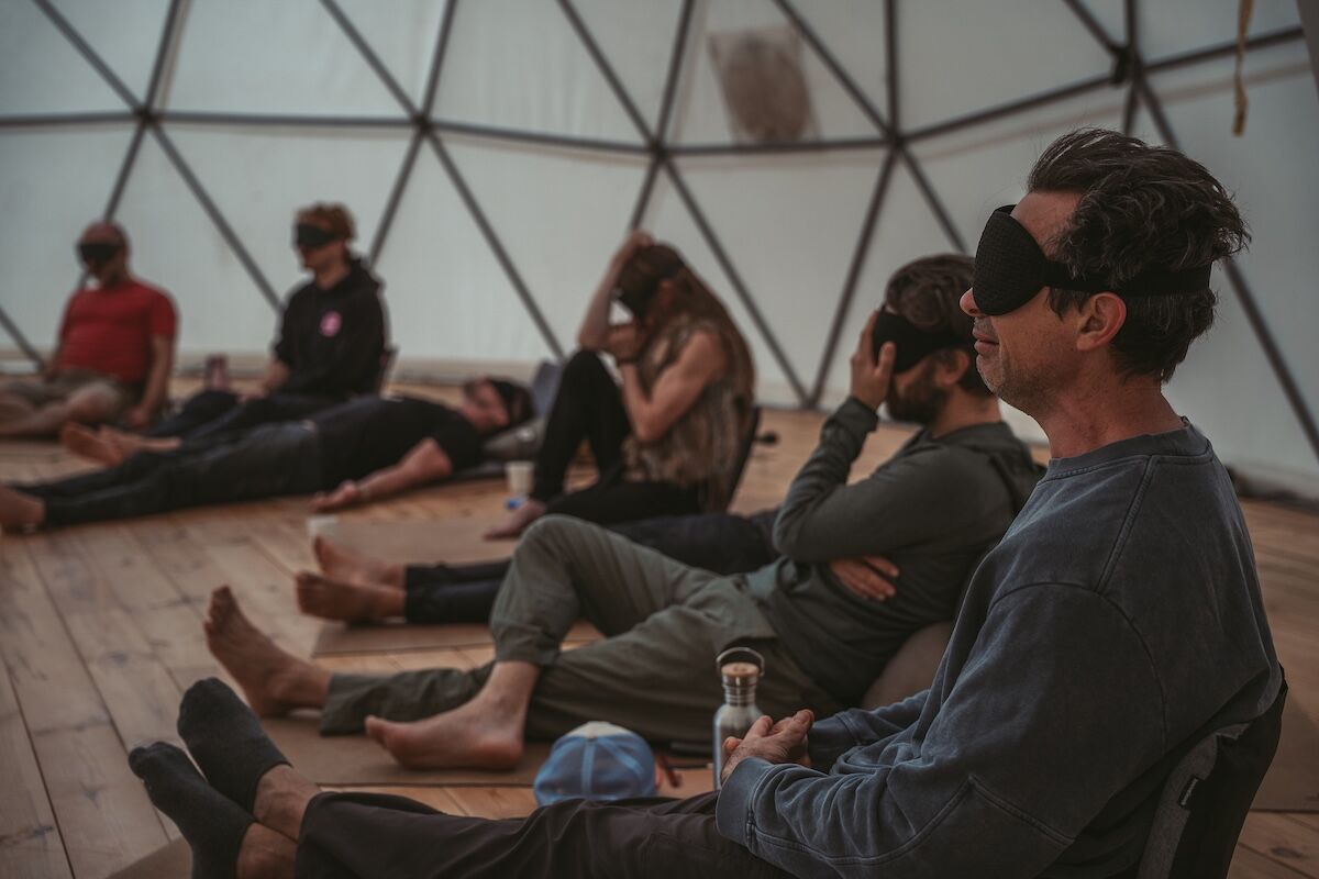 Blindfolded men rest on the dome floor during inner work at The Return of Men retreat, BioVilla, 2025.