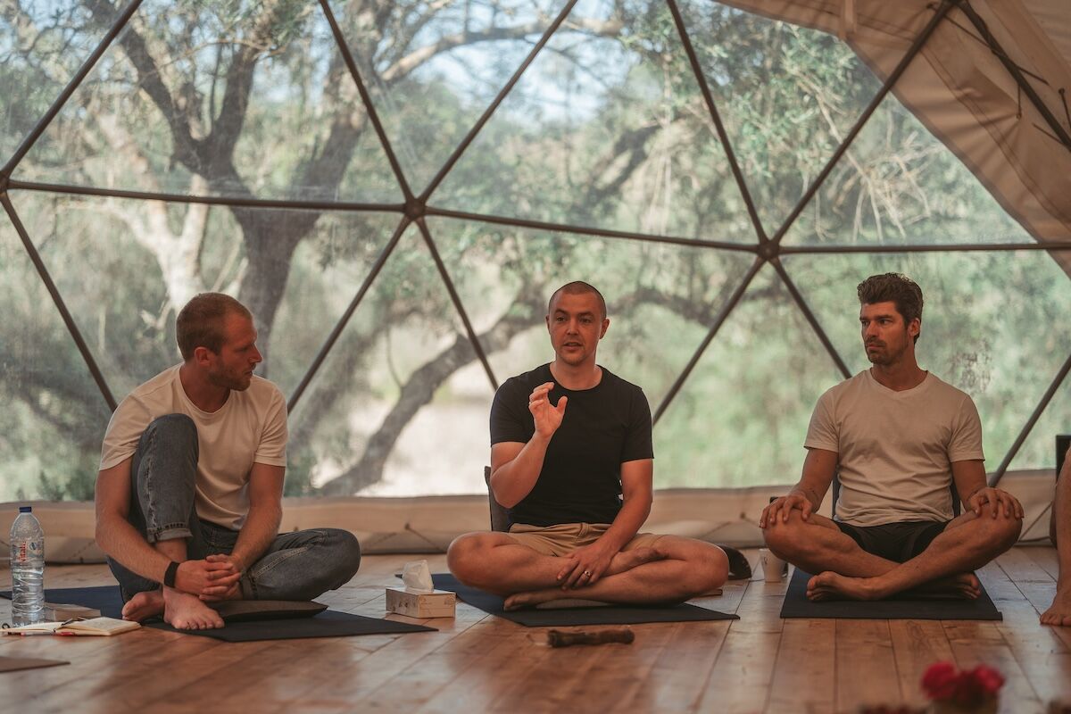 Three men sit cross-legged on mats in the geodesic dome at The Return of Men retreat, BioVilla, Arrábida.